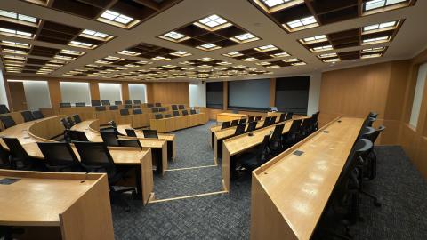 Large modern lecture hall with curved wooden seating and screens.